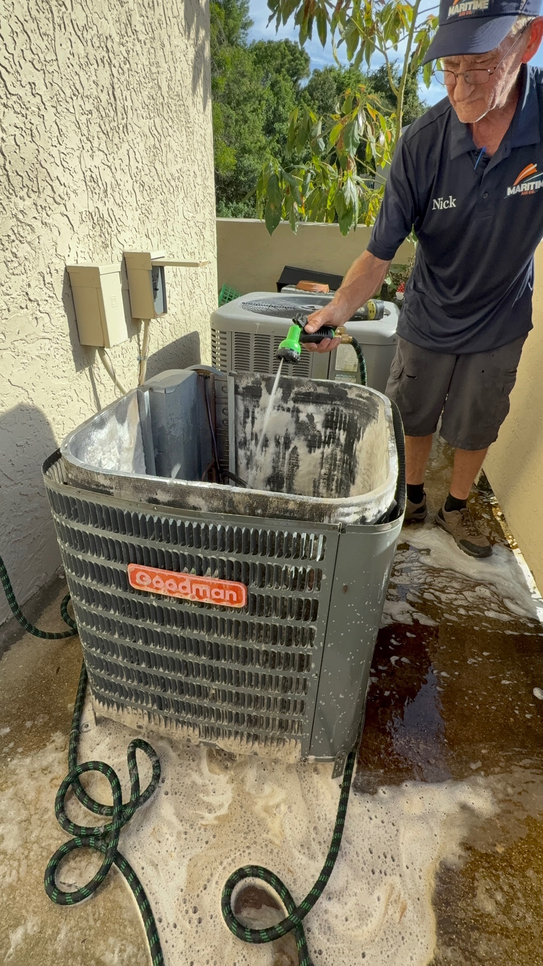 Maritime Air technician rinsing a Goodman condenser coil after a deep chemical clean in Fort Pierce, FL