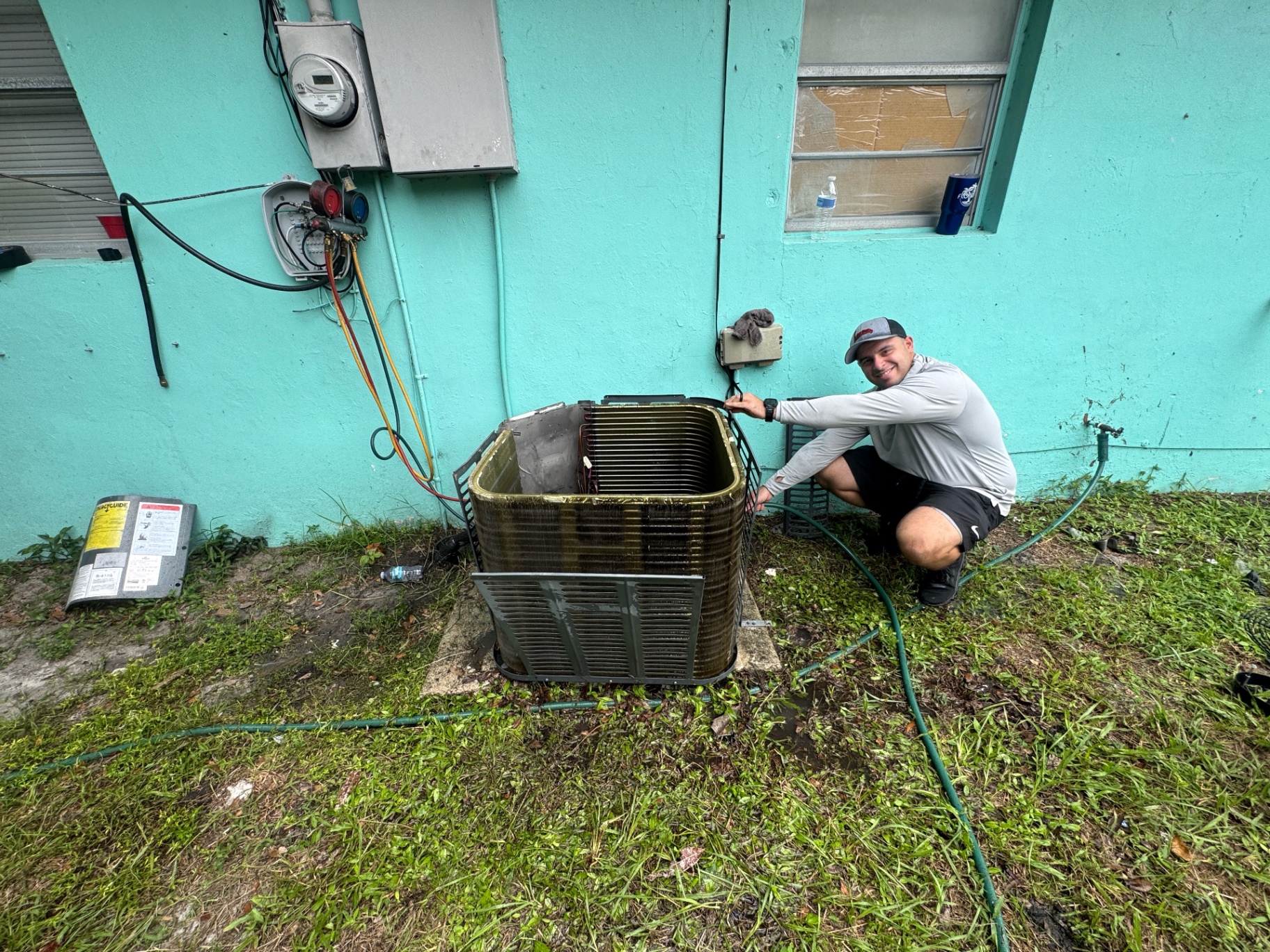 Michael cleaning a residential AC condenser coil with foaming cleaner in Fort Pierce, FL