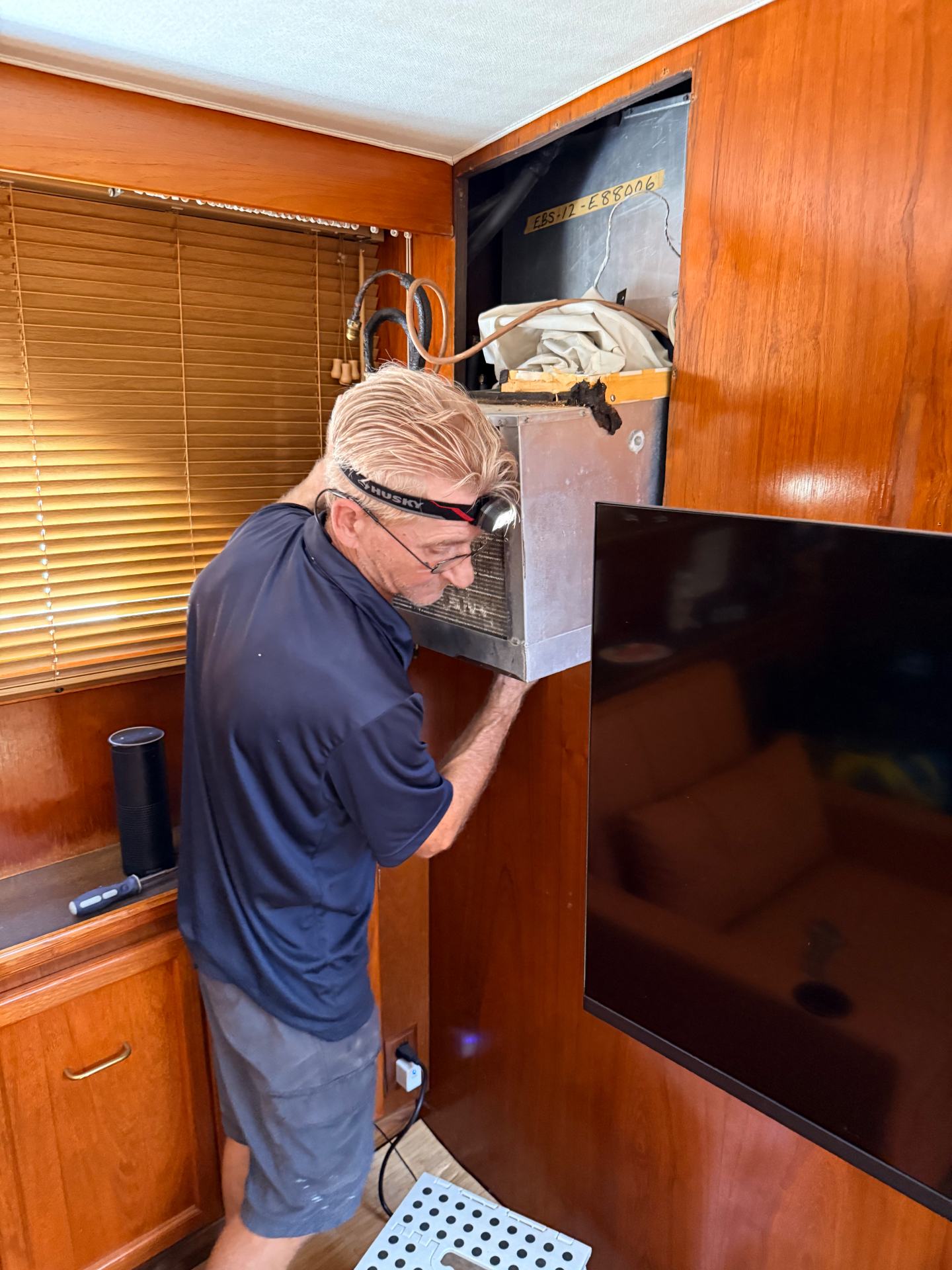 Maritime Air technician servicing a marine HVAC evaporator unit inside a yacht stateroom